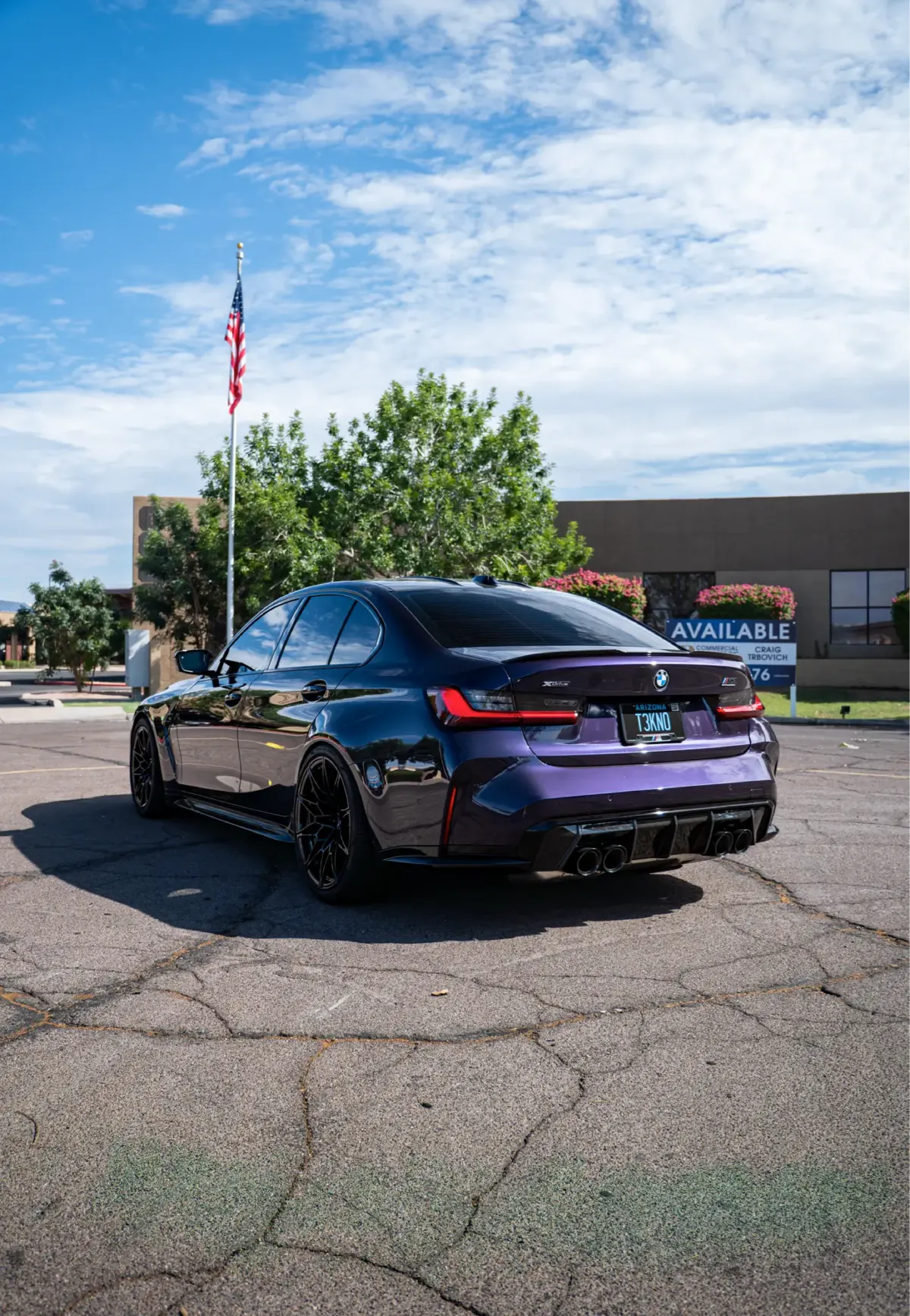 Purple BMW M3 (G80) sedan, rear three-quarter view, in a parking lot