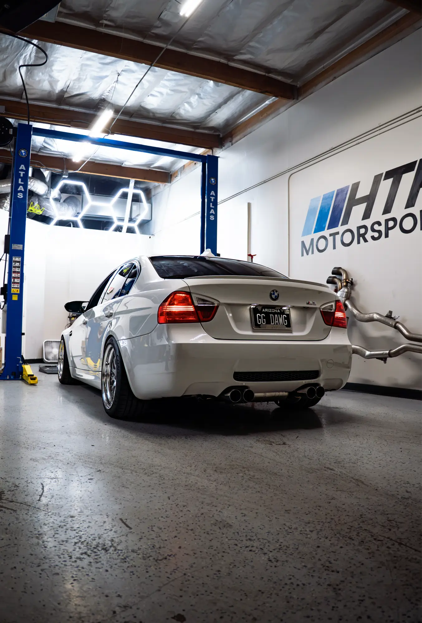 White BMW E90 M3 shown rear three-quarter at the HTP Motorsport shop.