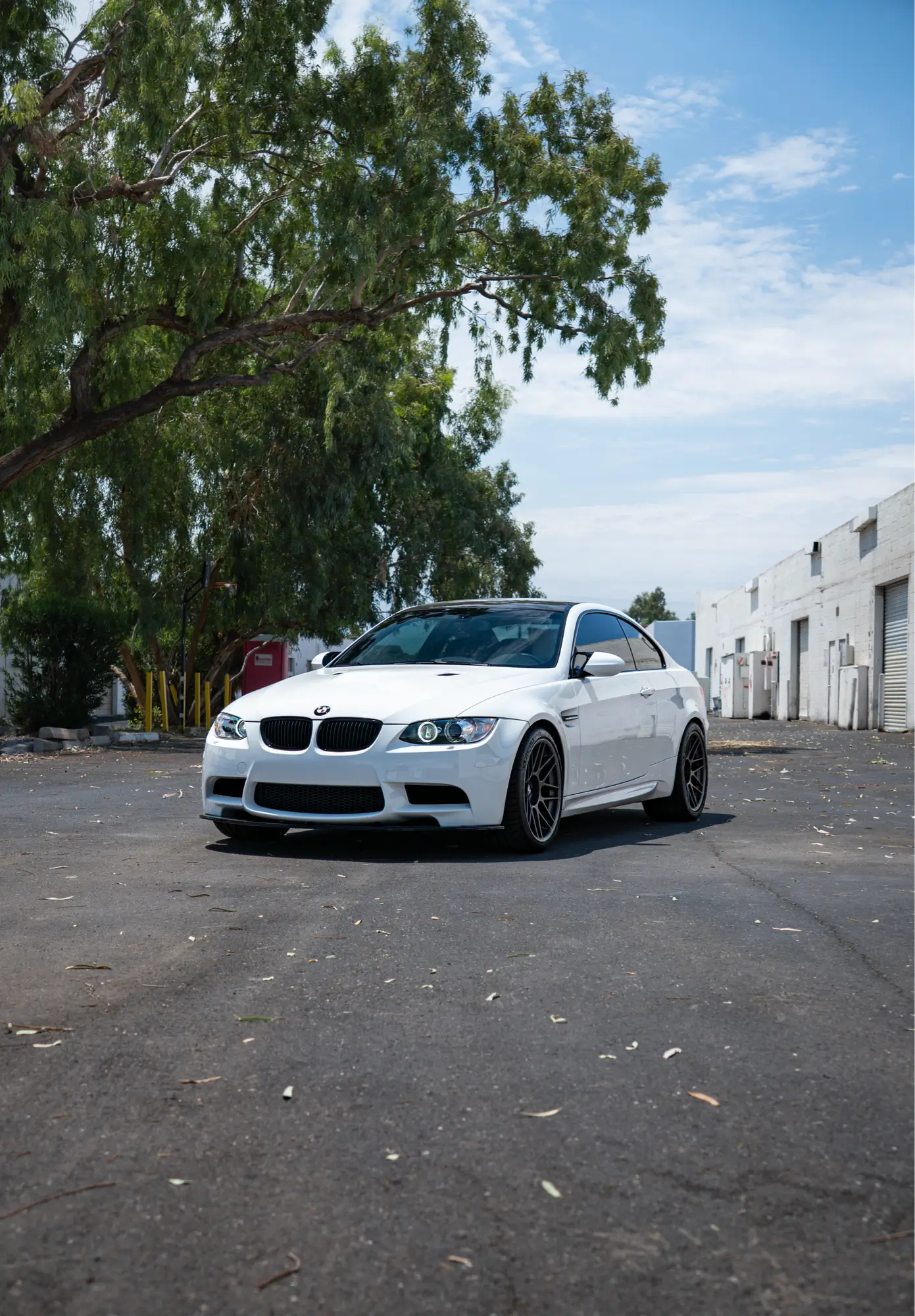 White BMW E92 M3 shown front three-quarter with trees in the background.