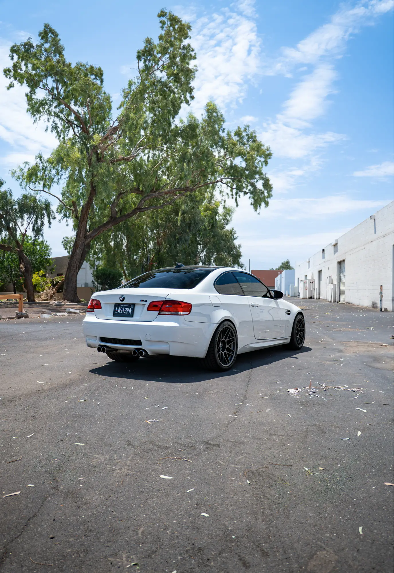 White BMW E92 M3 shown rear three-quarter with trees in the background.