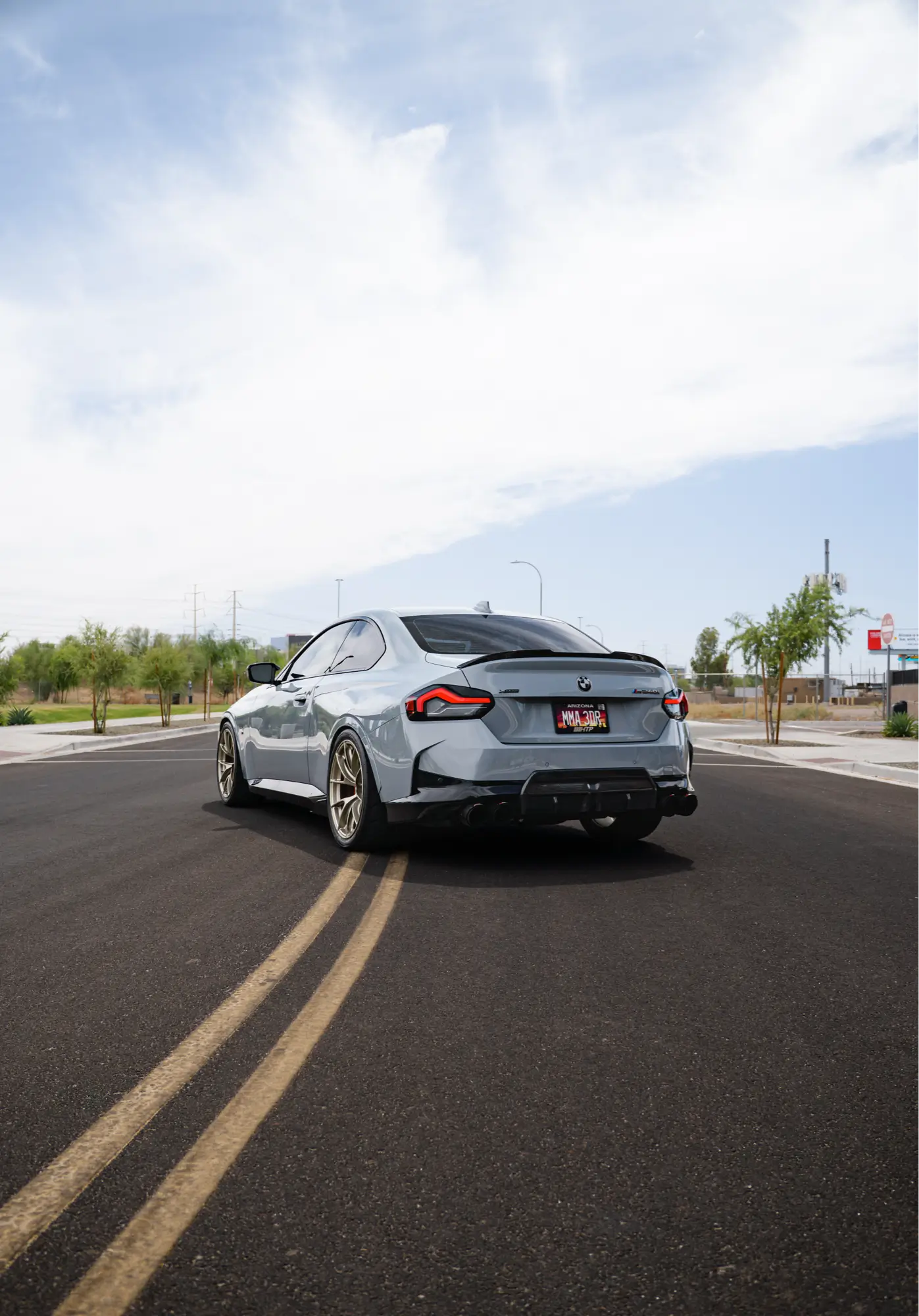 Grey BMW M240i (G42) shown rear three-quarter on gold wheels.