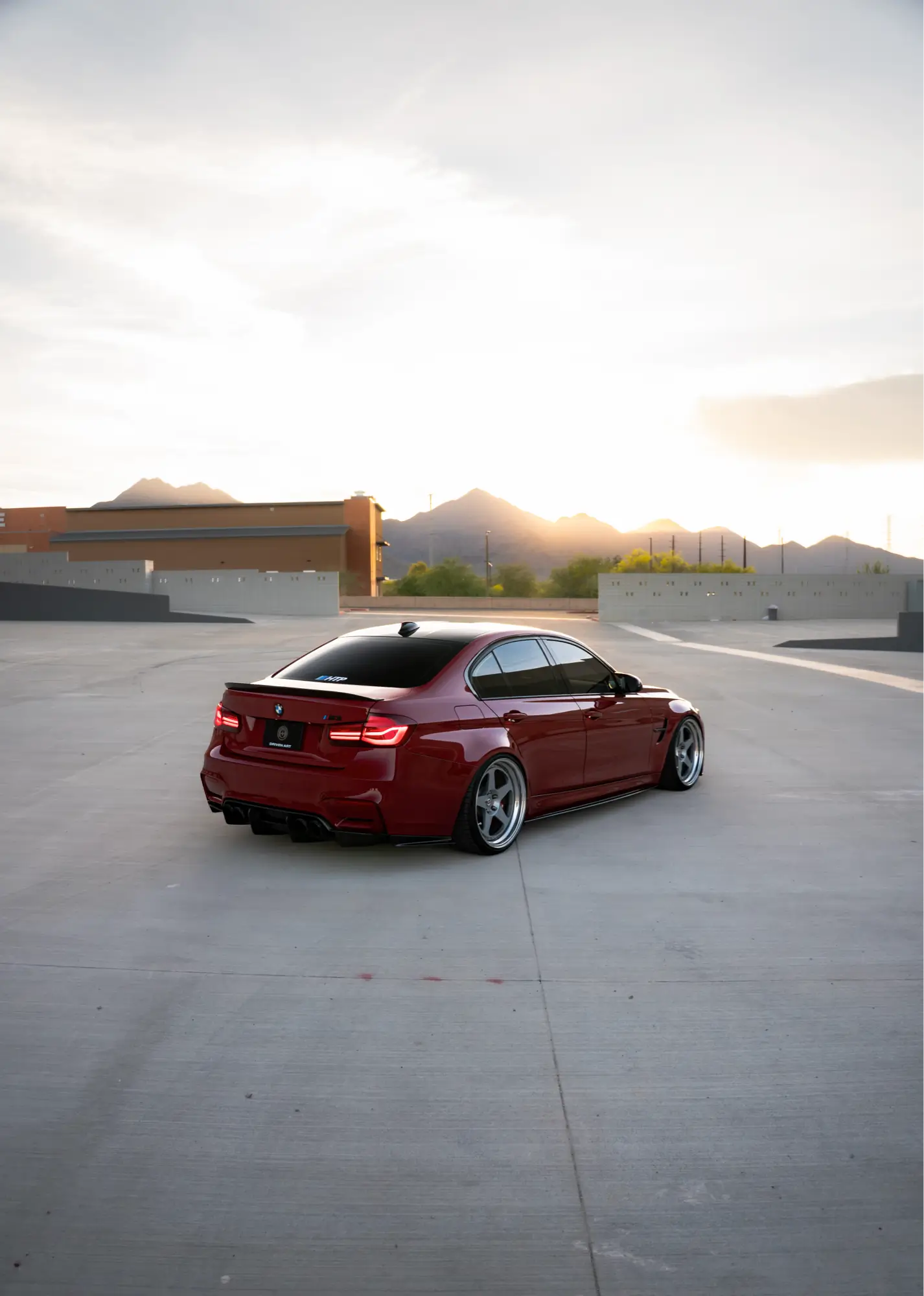 Maroon BMW M3 (F80) shown rear three-quarter in a rooftop parking lot.