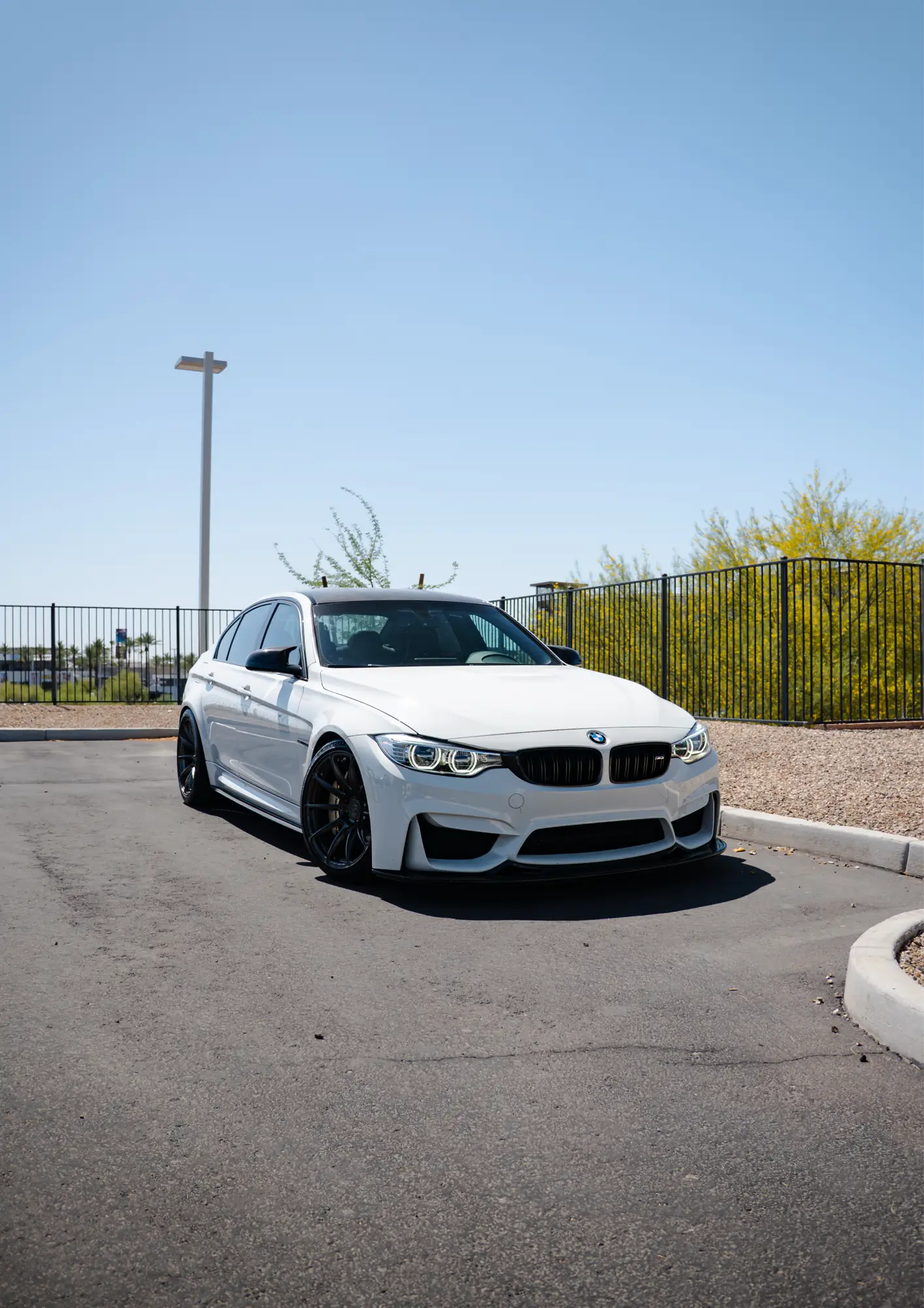 White BMW M3 (F80) on black wheels, shown front three-quarter.