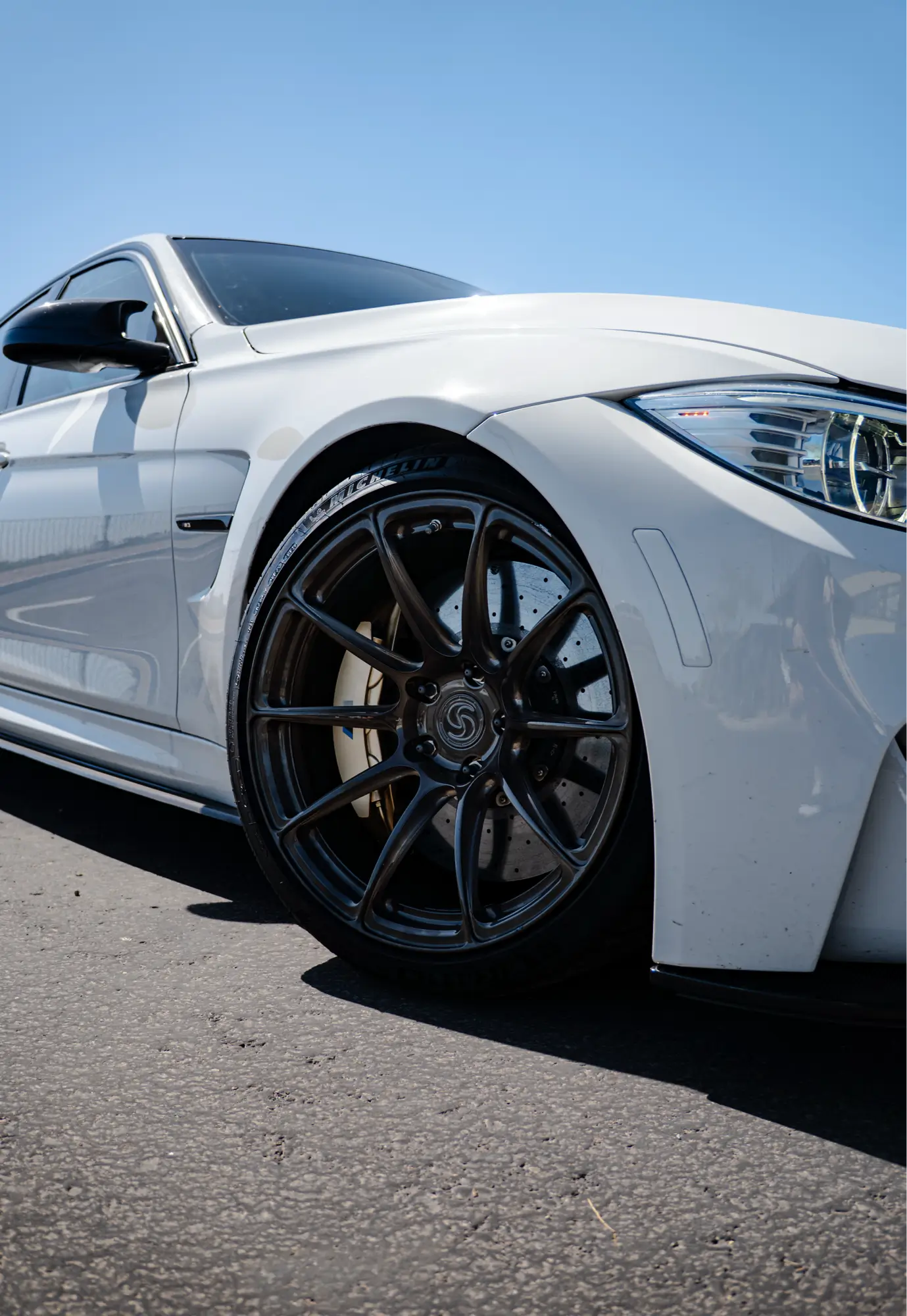 Close-up of a white BMW M3 (F80)'s front wheel.