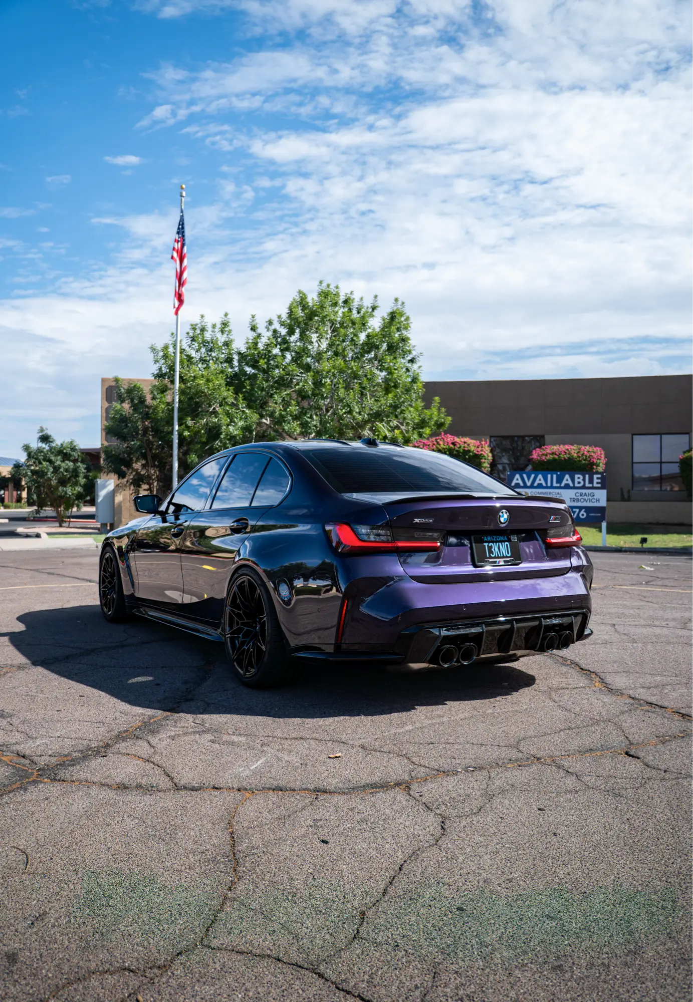 Purple BMW M3 (G80) shown rear three-quarter in a parking lot.