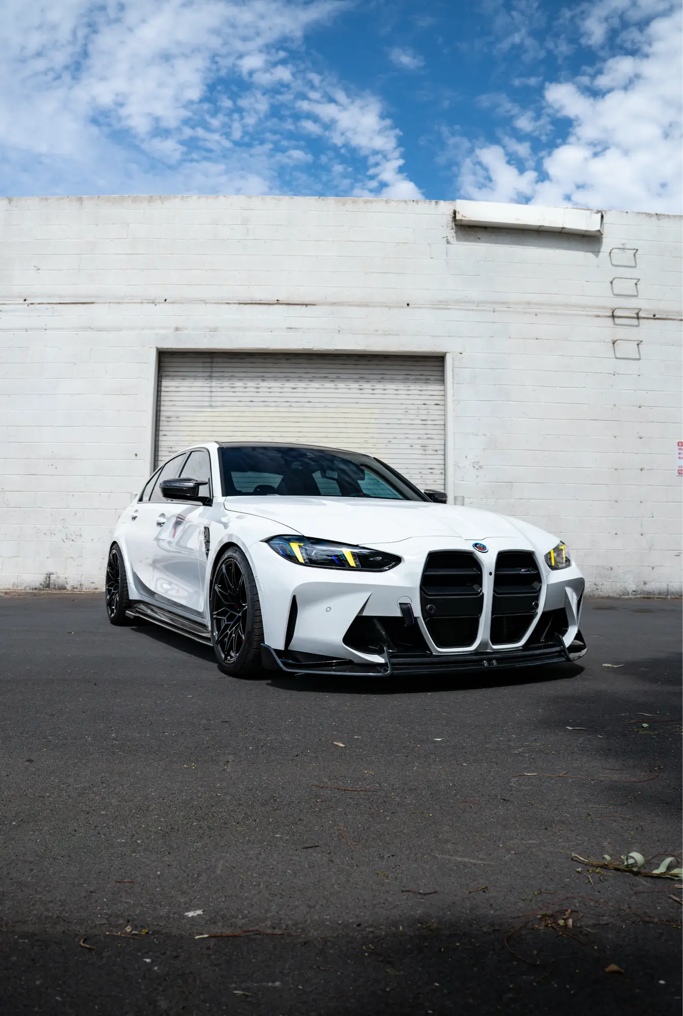 White BMW M3 (G80) shown front three-quarter inside a warehouse.