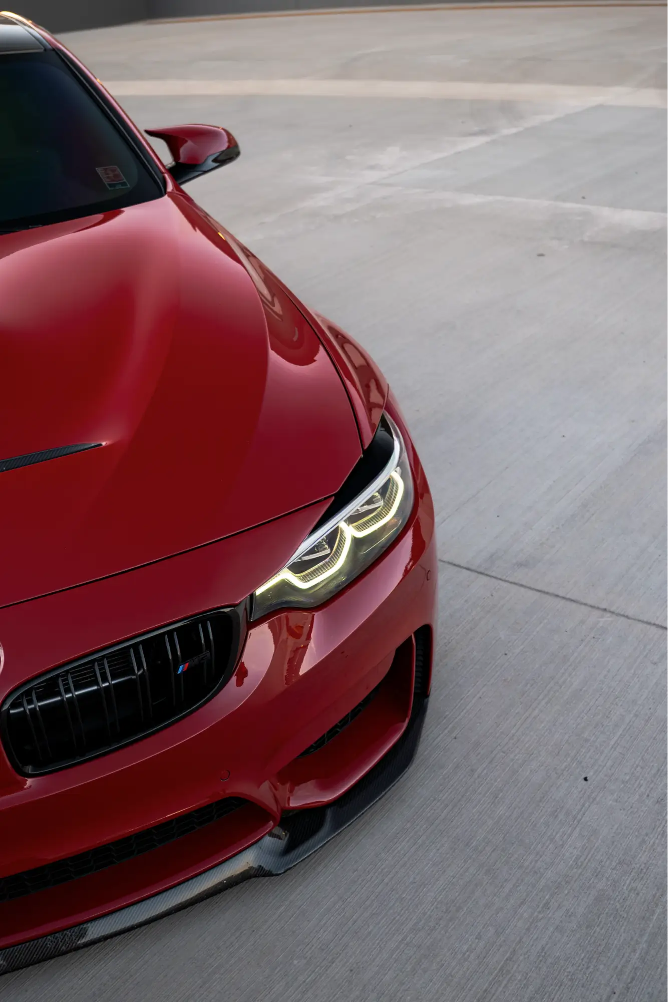 Close-up of a red BMW M3/M4 (F8x)'s front fascia and headlight.