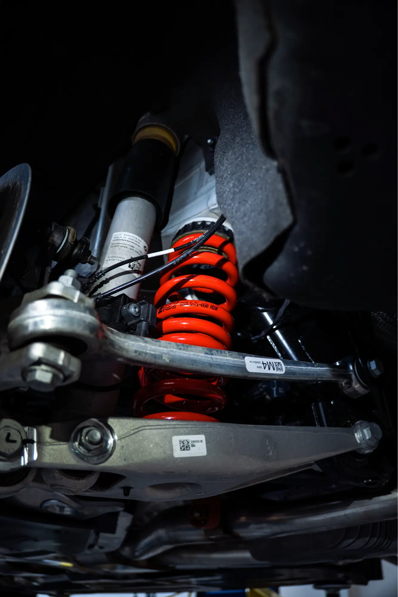 Close-up of a red BMW M4's rear coilover suspension.