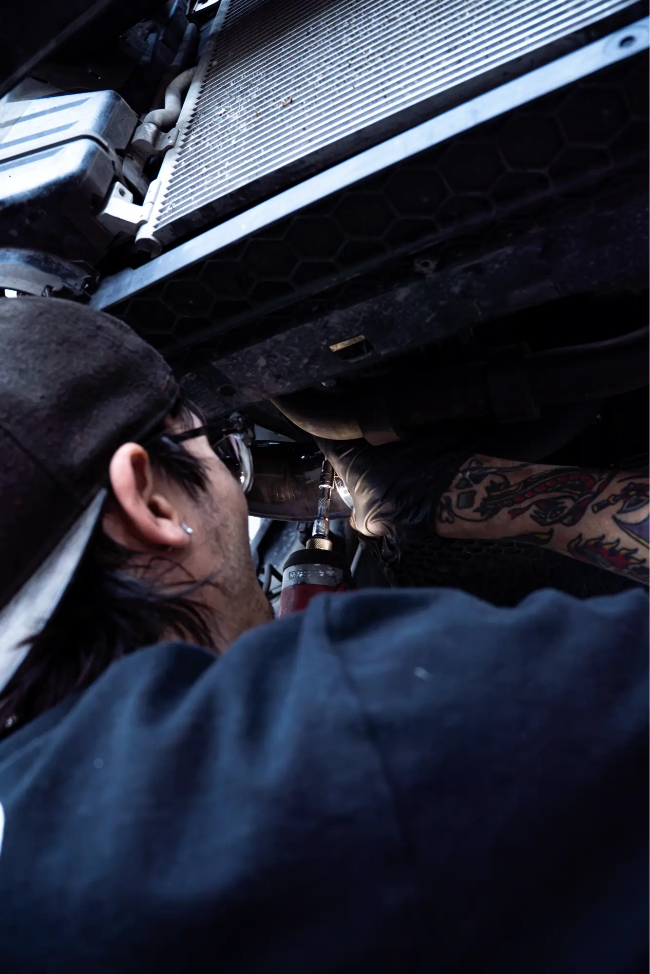 HTP Motorsport mechanic working underneath a car during radiator service.